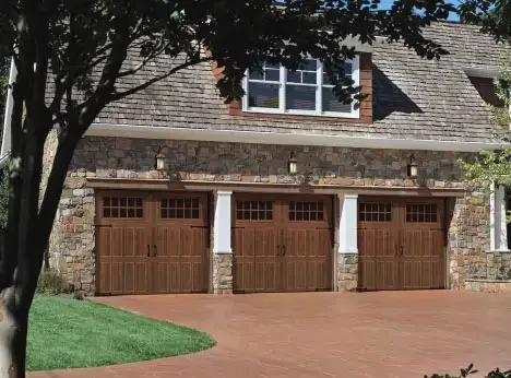 Wood carriage style garage doors on a stone and shingle home