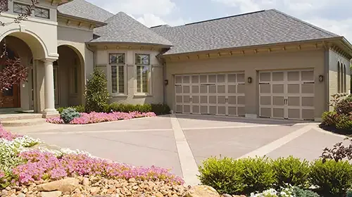 Stucco home with three garage doors and a landscaped driveway